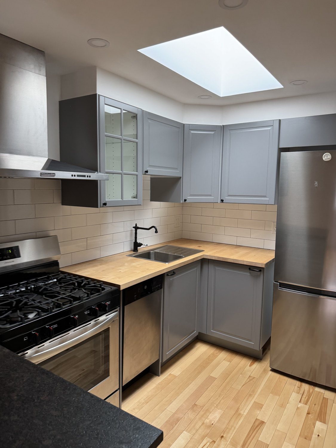 Clean kitchen with grey cabinets, stainless-steel appliances and clear worktops